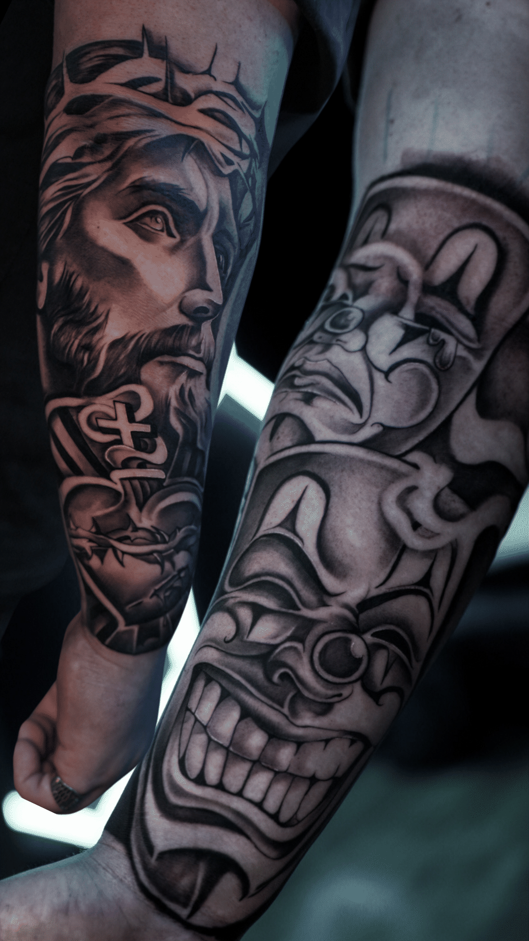 Two black and grey forearm sleeves, Jesus in a crown of thorns with a sacred heart, stacked clowns, Tagz Tattoo in Mesa, AZ