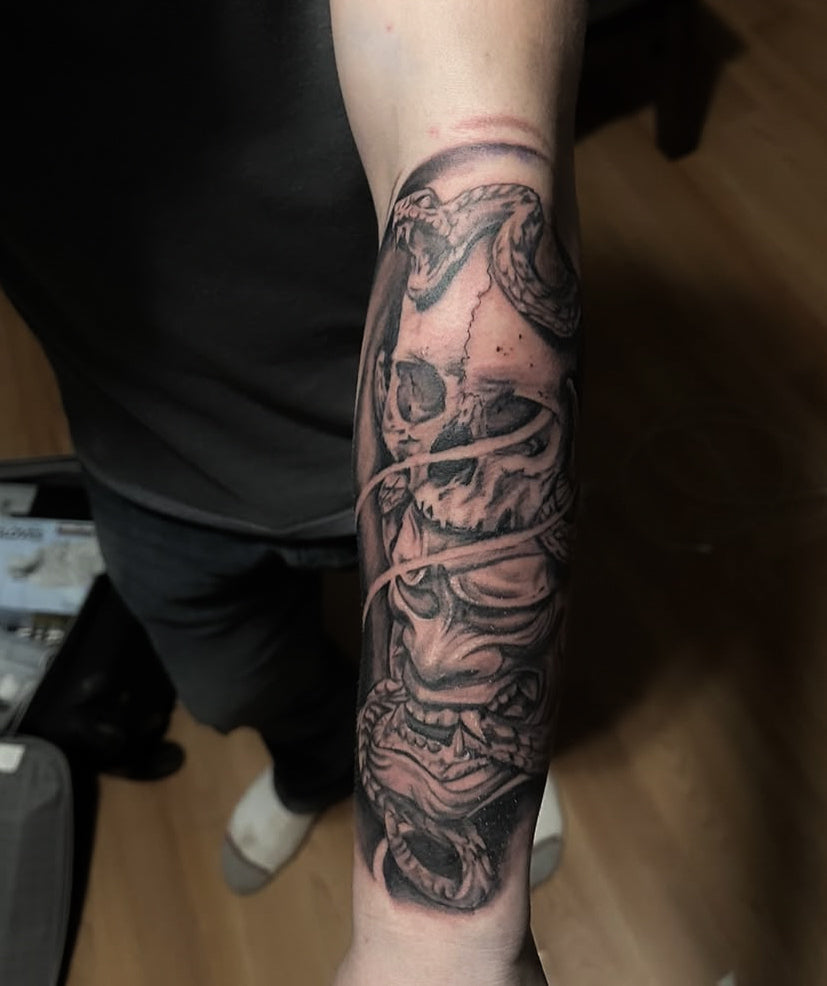 Black and grey skull, snake and hannya mask forearm sleeve tattooed at Tagz Tattoo in Mesa, AZ
