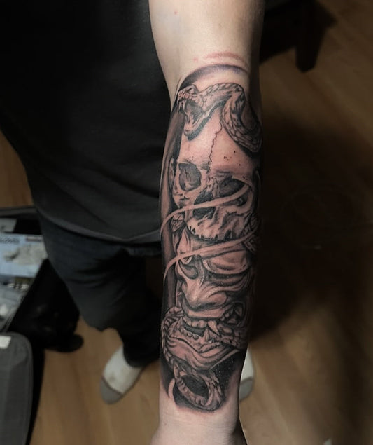 Black and grey skull, snake and hannya mask forearm sleeve tattooed at Tagz Tattoo in Mesa, AZ