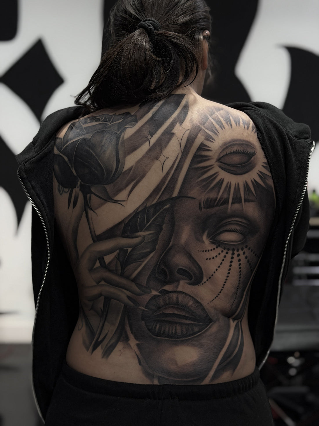Black and grey full back tattoo of a woman's face with a rose and a rayed sun
