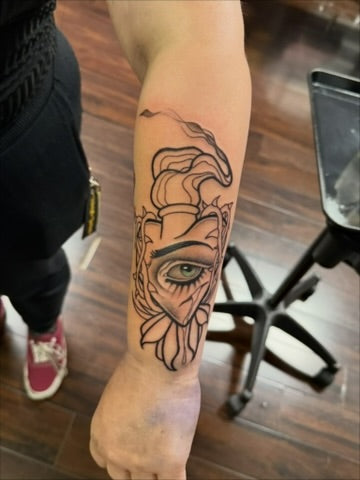 Illustrative face and eye forearm tattoo