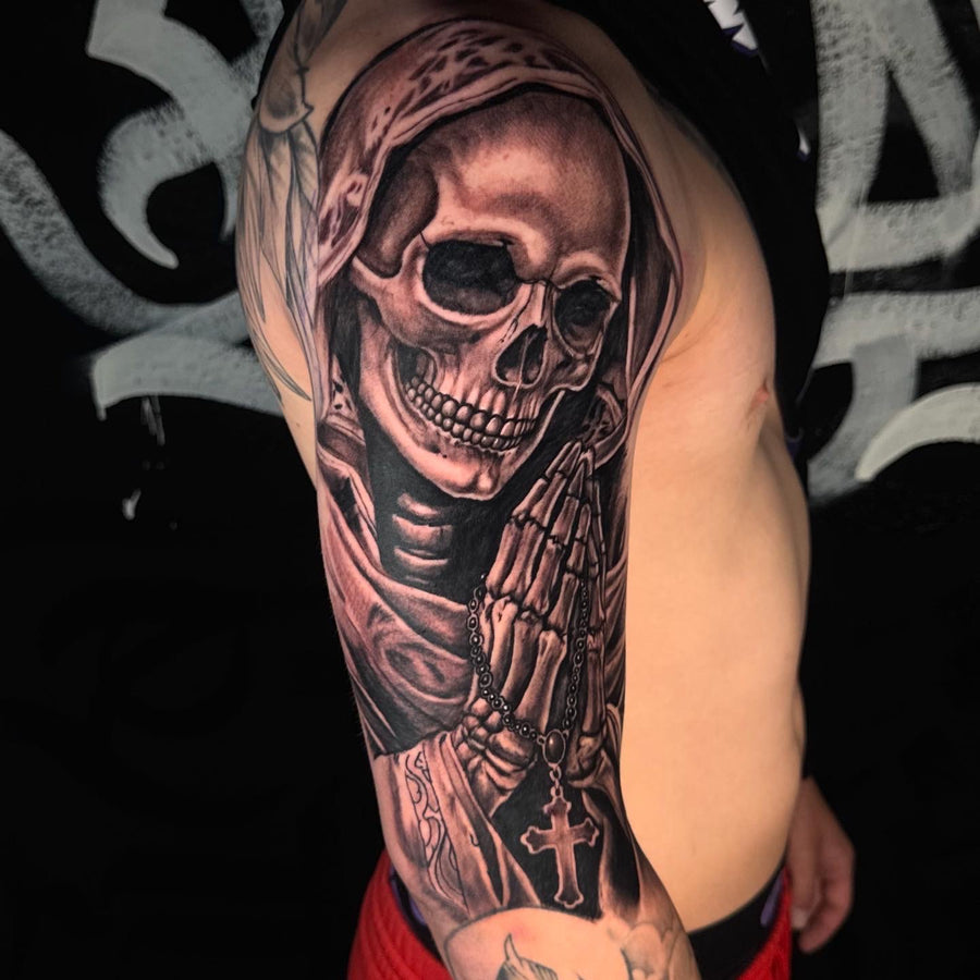 Black and grey skull and praying hands arm tattoo