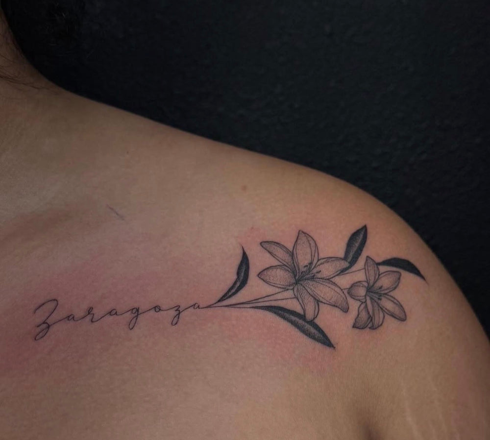Fine line floral shoulder tattoo with script lettering