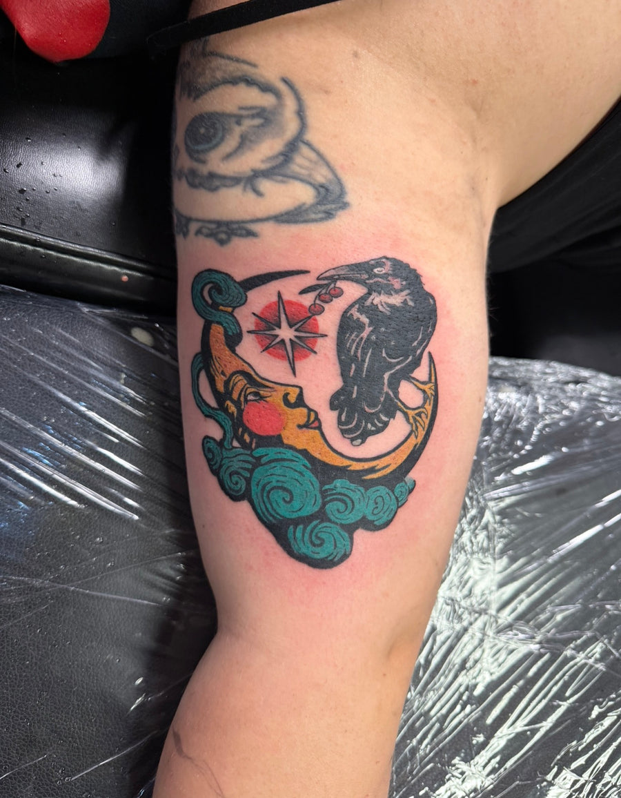 Color raven and moon tattoo on the upper arm