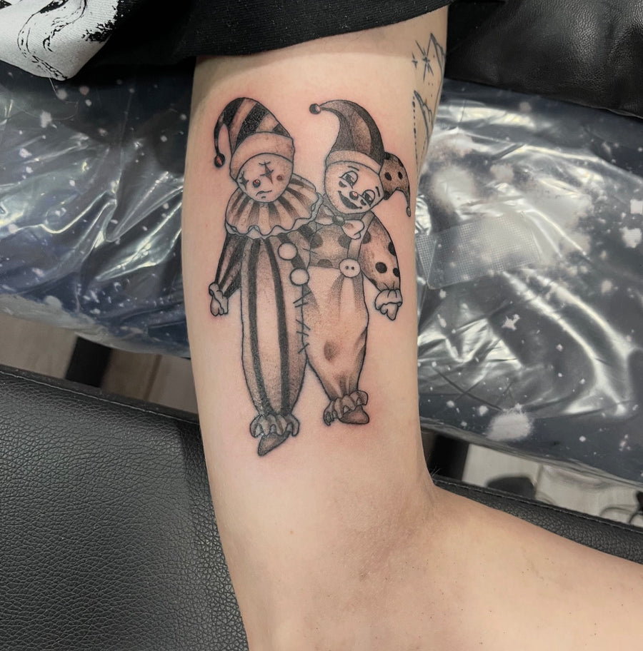 Fine line jester tattoo on the inner arm