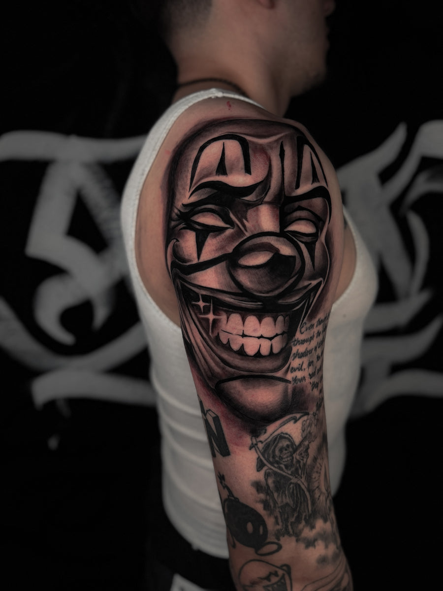 Black and grey clown mask shoulder tattoo