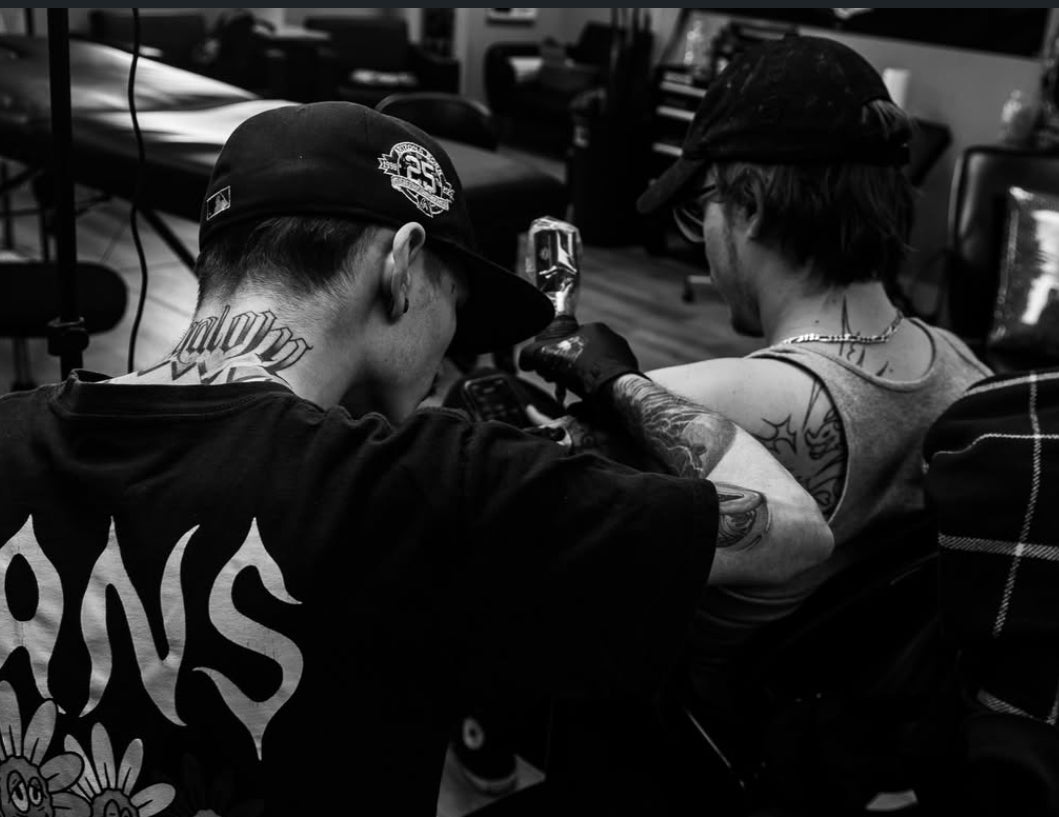 Tattoo artist at work on a client's upper arm inside the Tagz Tattoo studio in Mesa, AZ